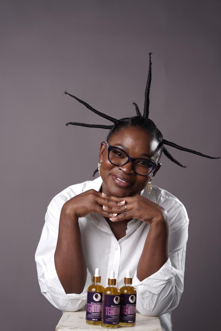 Femme allongée, cheveux afro entourés de flacons TERMINUS